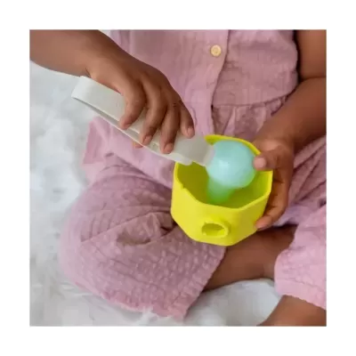 Criança com tigela de silicone amarela e colher azul segurando um recipiente branco