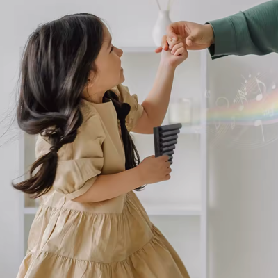 Menina com vestido bege segura flauta preta e interage com adulto em fundo interno branco