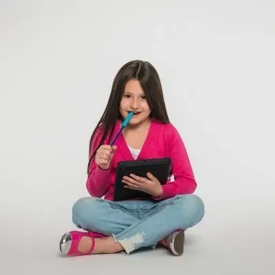 Menina sentada no chão segurando caneta e tablet com fundo branco
