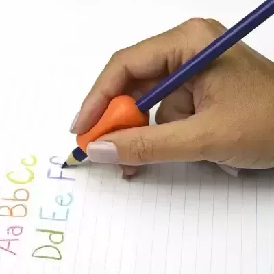 Mão a segurar lápis azul com pega de silicone alaranjada a escrever letras coloridas numa folha pautada