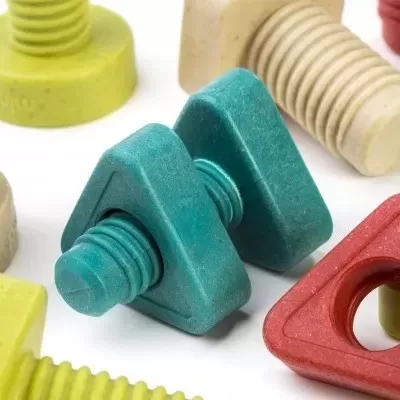 Parafuso de plástico verde triangular com outros parafusos coloridos num fundo branco