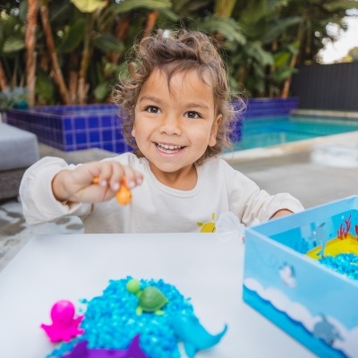 Criança a brincar com brinquedo de água colorido ao ar livre junto a piscina