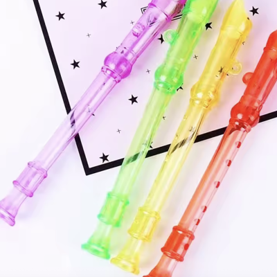 Quatro flautas doce de plástico coloridas transparentes sobre fundo branco com estrelas pretas.