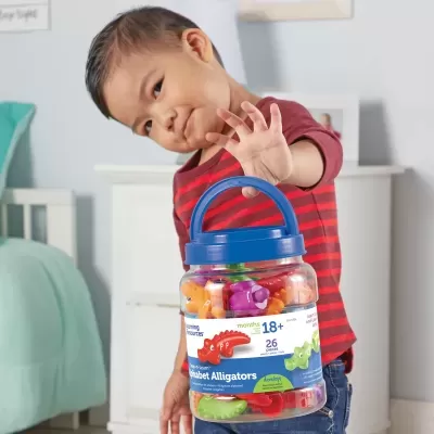 Criança com frasco de brinquedos de aligátor coloridos em quarto