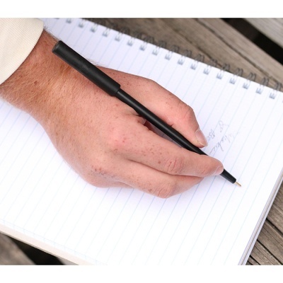 Mão a escrever com caneta preta em caderno espiral com folhas pautadas