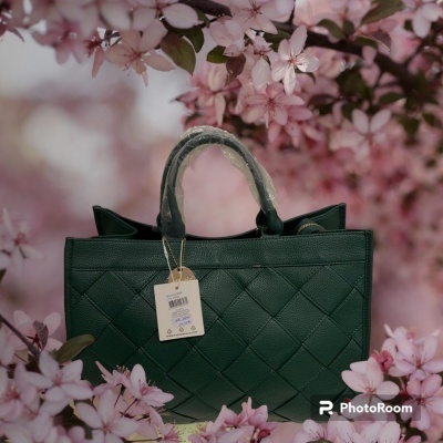 Bolsa preta com textura quadriculada junto a flores cor-de-rosa