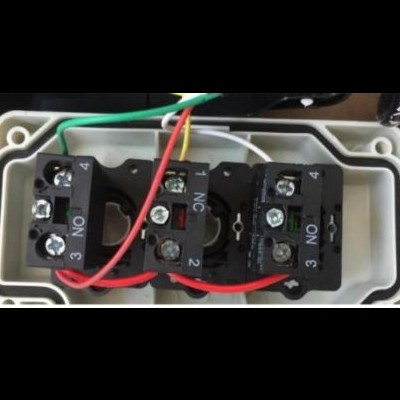 Componente elétrico com interruptores e fios coloridos numa caixa plástica branca