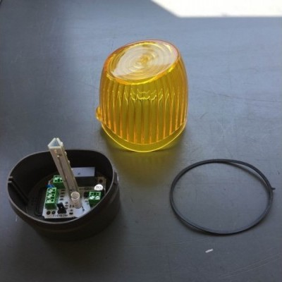 Luz de aviso amarela com base preta e anel de vedação num fundo cinza