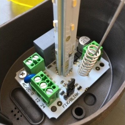 Placa eletrónica com componentes verdes e preta com texto AC-DC e TX/BLINK