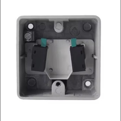 Caixa elétrica quadrada cinza com interruptores pretos e detalhes azul-esverdeado.