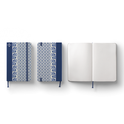 Três cadernos, dois com capas azuis e brancas padrão geométrico, um aberto com páginas em branco