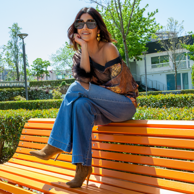 Mulher sentada num banco laranja de madeira no parque