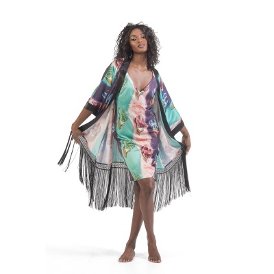 Vestido floral colorido com capa preta de franjas numa modelo em fundo branco