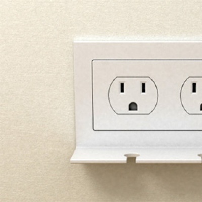 Tomada dupla embutida com suporte plástico branco numa parede creme