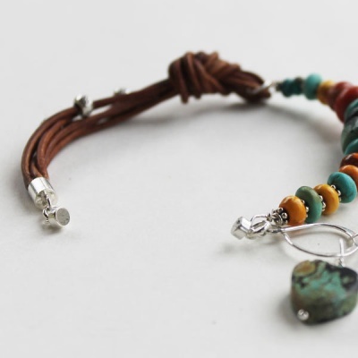 Pulseira com cordão castanho, contas coloridas e pendente em forma de coração verde