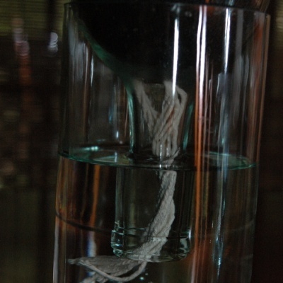 Copo de vidro com água e uma corda branca dentro