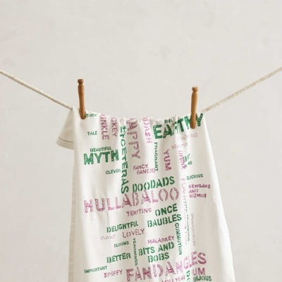 Toalha branca com palavras coloridas pendurada num estendal