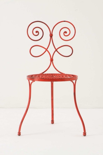 Cadeira vermelha de metal com design em espiral e assento redondo em malha