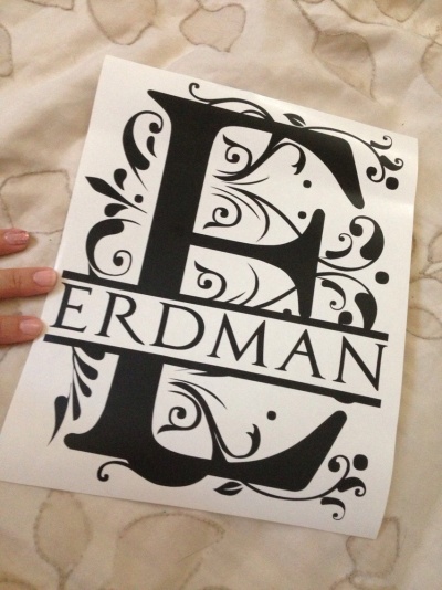 Cartaz branco com letra preta decorativa 'E' e texto ERDMAN sobre cama clara com padrão de corações