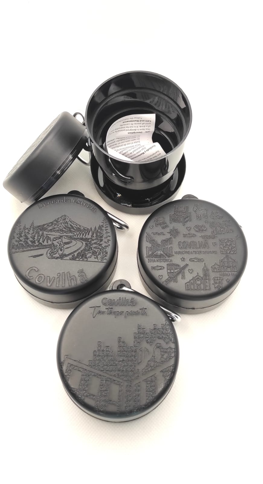 COPO PP DOBRÁVEL LIVRE DE BPA 220 ml Recipientes redondos pretos com tampas decoradas e papel dentro de um deles.