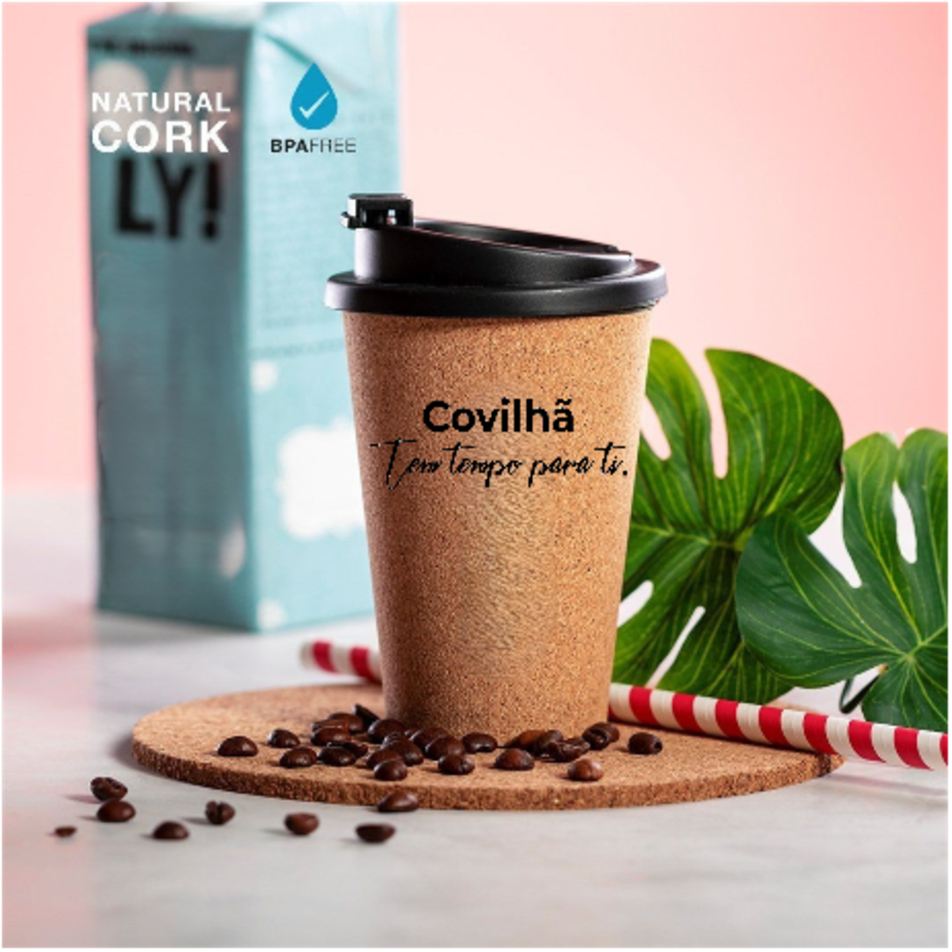 COPO PP REVESTIDO EM CORTIÇA 350 ML Copo de cortiça com texto e grãos de café sobre suporte redondo de cortiça com folha e canudo ao fundo