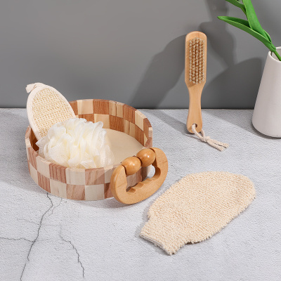 Conjunto de acessórios de banho em madeira e tecidos creme numa superfície cinzenta.