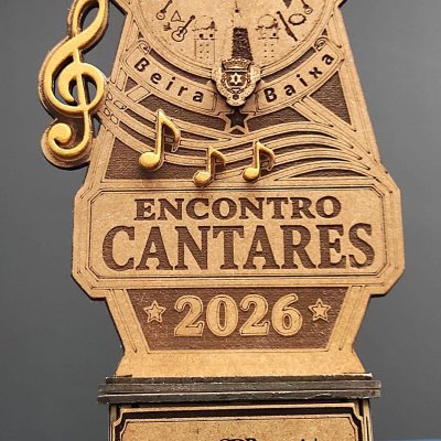 Troféu de madeira com tema musical e inscrições alusivas a grupo de cantares e evento de 2026