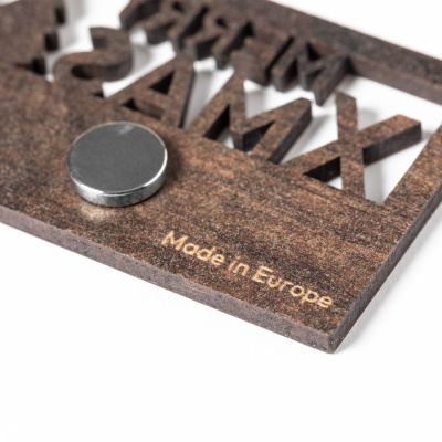 Placa de madeira escura com letras recortadas e texto Made in Europe com íman redondo prateado