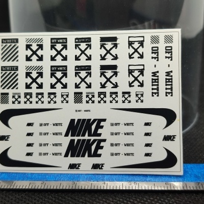Adesivos preto e branco com textos NIKE e OFF-WHITE sobre superfície preta
