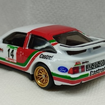 Miniatura de carro de corrida branco com detalhes vermelhos e verdes e rodas douradas.