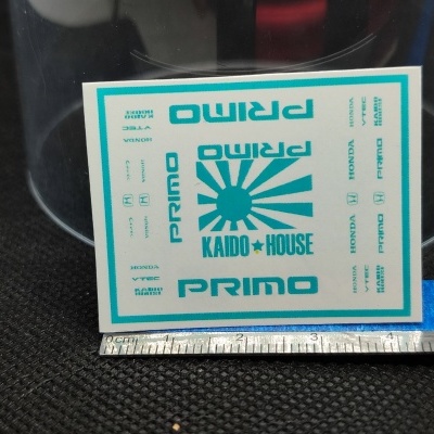 Autocolantes com texto azul e branco sobre superfície preta com régua em metal