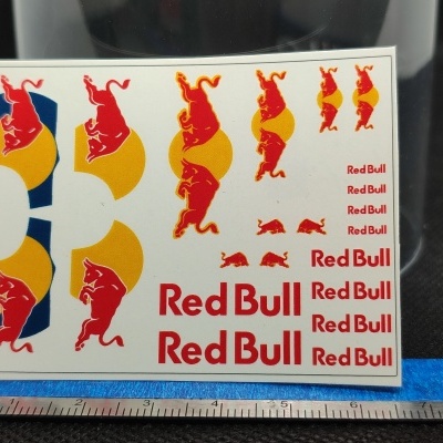 Folha de autocolantes Red Bull com logotipos e textos em vermelho e amarelo sobre fundo branco.