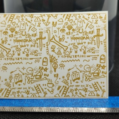 Caixa branca com decoração dourada com vários desenhos e texto HOONIGAN e JUST DONT DIE.