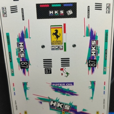 Autocolantes temáticos de carros com logotipos Ferrari e HKS em folha branca com padrão gráfico colorido
