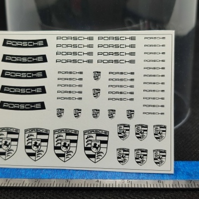 Folha de autocolantes com logótipos e escudos Porsche e régua na base.