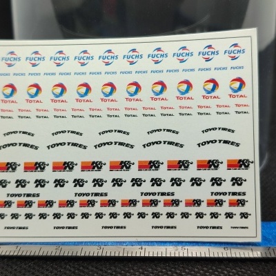 Folha de autocolantes com logos de marcas automóveis e régua em metal