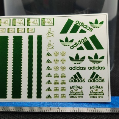Folha de autocolantes Adidas verdes com régua azul e metálica em fundo preto