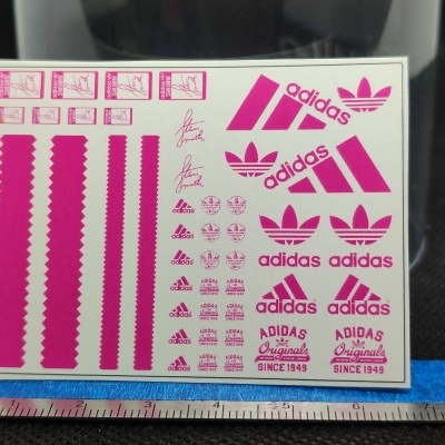 Folha de autocolantes rosa com logótipos Adidas e texto sobre fundo branco