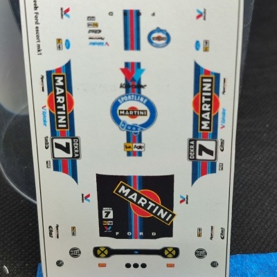 Folha de decalques Martini Racing para modelo de carro com régua em fundo preto.