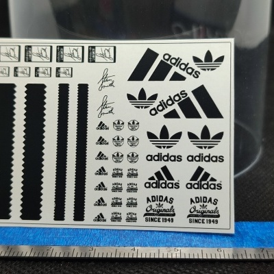 Folha de autocolantes com logótipos preto da adidas sobre fundo branco.