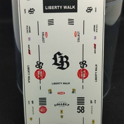 Folha branca com autocolantes para maquete automóvel Liberty Walk e Ferrari sobre fundo preto e régua