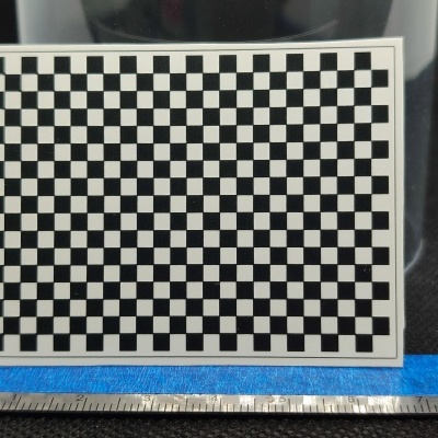 Tabuleiro de xadrez preto e branco junto a régua de 8 cm sobre superfície preta e azul