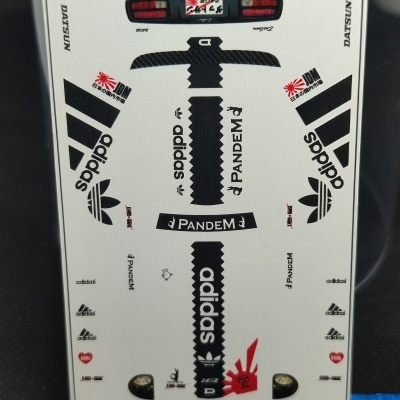 Folha de decalques para modelo Hot Wheels Datsun 240Z com logos Adidas, Pandem, e texto em fundo branco.