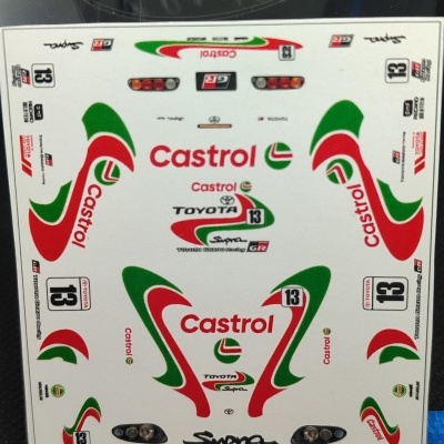 Folha de decalques para modelo de carro Toyota Supra com logos Castrol, Toyota, números 13 e régua na base.