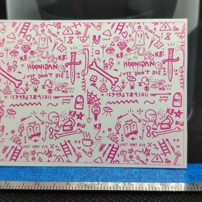 Cartolina com desenhos e textos em rosa, escala em centímetros em fundo escuro