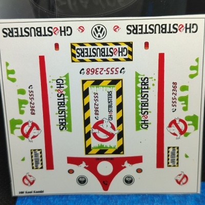 Folha de autocolantes Ghostbusters com logos, texto e números em várias cores sobre fundo branco e régua em baixo.