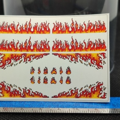 Autocolantes de chamas coloridas sobre fundo branco com régua em baixo.
