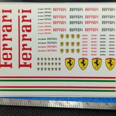 Folha de autocolantes Ferrari com texto, símbolos e riscas coloridas em fundo branco