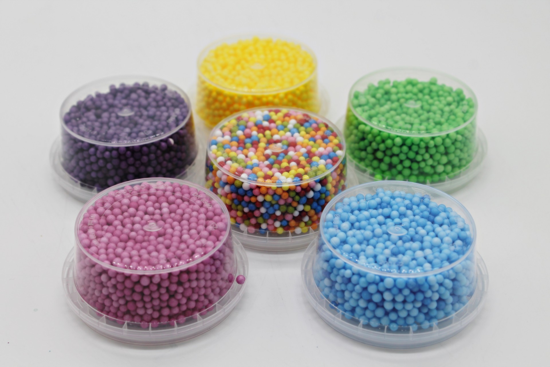 Seis recipientes com pérolas coloridas sobre fundo branco