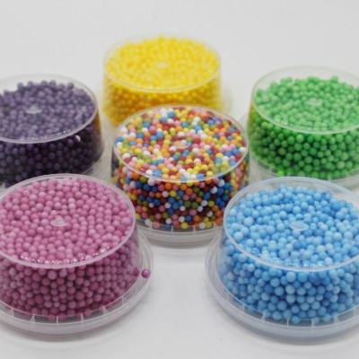 Seis recipientes com pérolas coloridas sobre fundo branco